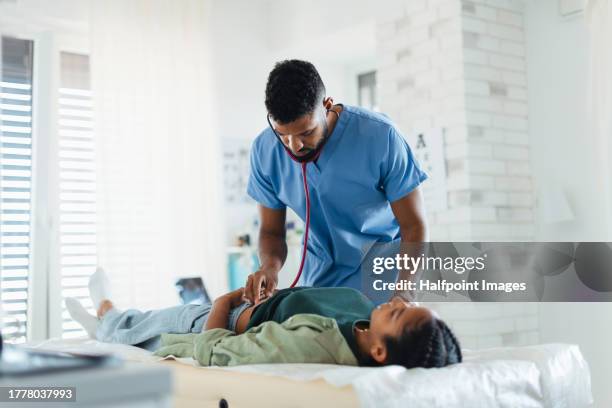 doctor listening for bowel sounds of teenage girl’s abdomen, using stethoscope. teenager visiting paediatrician for annual preventive physical examination. concept of preventive health care for adolescents. - milz stock-fotos und bilder
