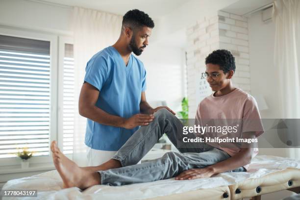 doctor checking the mobility of teenage boy's knee. orthopedist examining and treating painful injured knee of young athlete. concept of preventive health care for adolescents. - padding stock pictures, royalty-free photos & images