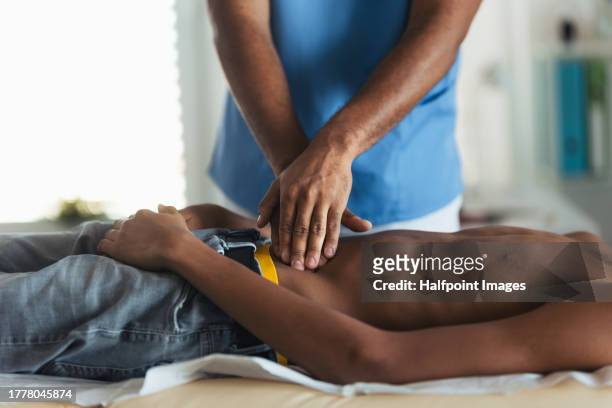 close up of doctor palpating teenage boy's abdomen, using hands and steady pressure. boy visiting paediatrician for annual preventive physical examination. concept of preventive health care for adolescents - slovakia vaccine stock pictures, royalty-free photos & images