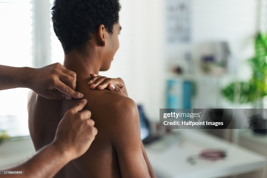 Close up of doctor examining teenage boy's skin, checking acne and moles. Skin cancer screening. Boy visiting dermatologist for annual preventive annual exam. Concept of preventive health care for adolescents.