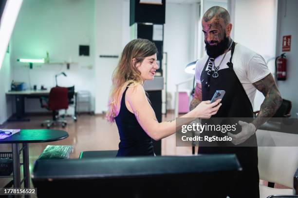 girl showing a tattoo idea to her tattoo artist - pierced stockfoto's en -beelden