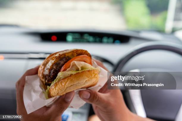 man eating hamburger in car. - car grill stock pictures, royalty-free photos & images
