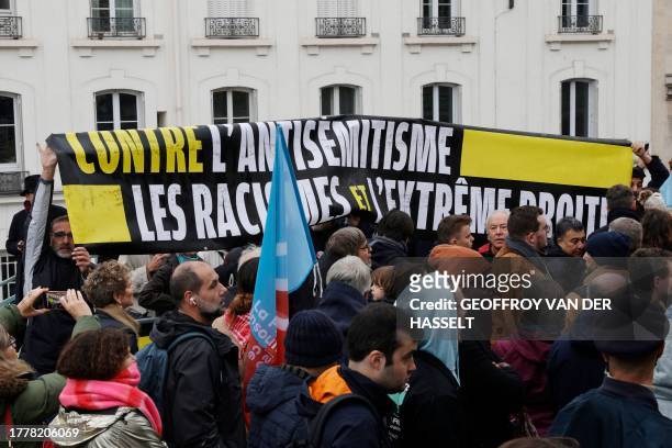 People hold a banner reading "Against anti-Semitism, the racisms and the far right" as they take part in a gathering organised by La France Insoumise...