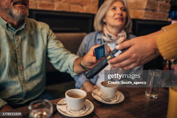 mature couple paying with credit card in the cafe - business mature couple portrait stock pictures, royalty-free photos & images