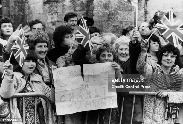 Royal fans waving small British flags and holding a message reading 'Come On Charlie, You Are Next' outside the wedding of Lord Romsey and Penelope...