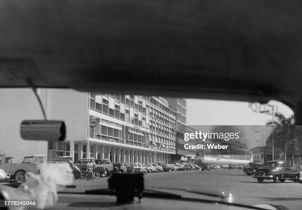 View through the windscreen of a vehicle showing cars parked along a boulevard in the centre of Luanda, Angola, circa 1965.