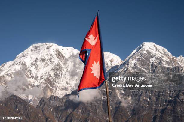 nepali flag with beautiful view of mt.annapurna south (7,219 m) and mt.hiunchuli (6,441 m) seen from mardi himal view point in the annapurna region of nepal. - nepal flag stock pictures, royalty-free photos & images