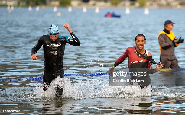 Chris McCormack and Jeff Symonds exit the water after completing the swim portion of the Challenge Penticton Triathlon on August 25, 2013 in...