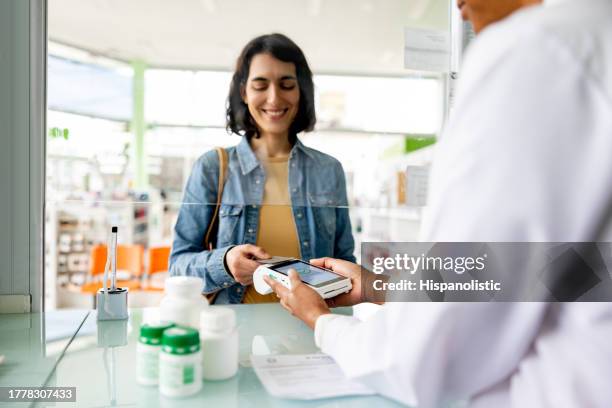 woman paying by card while buying medicines at the pharmacy - payment bildbanksfoton och bilder