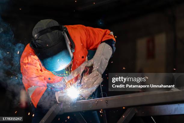 artesanos dedicados, vestidos con equipos de seguridad, han presentado una técnica innovadora para soldar superficies metálicas, lo que da como resultado un acabado impecablemente suave y excepcionalmente resistente. innovación y progreso en el ámbito - soldar fotografías e imágenes de stock