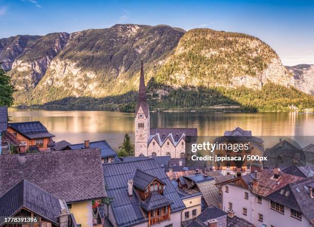 high angle view of houses by lake against mountain - church tower restoration appeal stock pictures, royalty-free photos & images