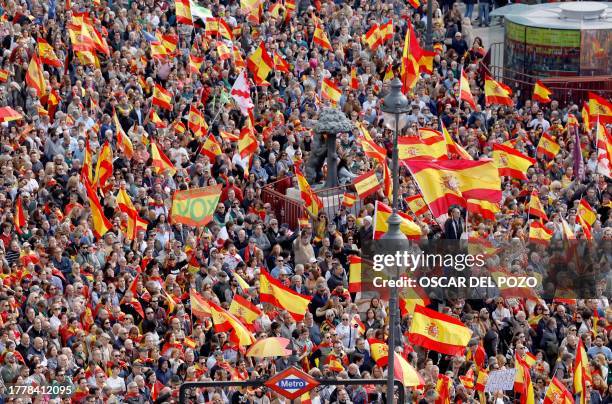 Demonstrators hold Spain's flags and a Spain's flag with far-right Vox party name during a protest called by right-wing opposition against an amnesty...