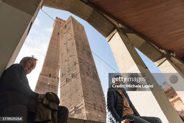 People take a break sitting under the arcades near the 'Two Towers' on November 06, 2023 in Bologna, Italy. The 48-meter tower was built in the 12th...