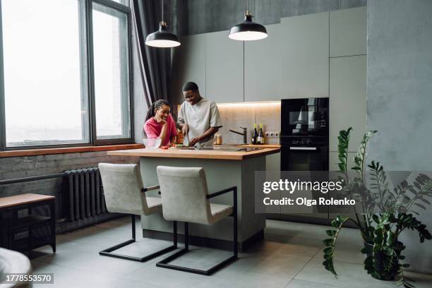 boyfriend cooking for his girlfriend in modern kitchen. dark skin woman look at her boyfriend, master chef - placa de fogão vitrocerâmica imagens e fotografias de stock