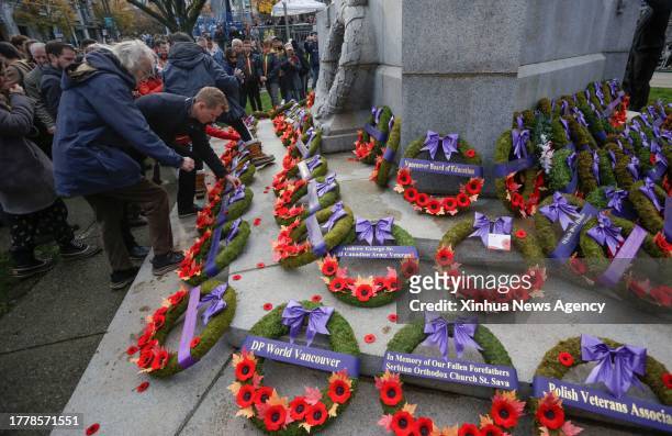 People place poppies in front of a cenotaph during the Remembrance Day ceremony at Victory Square in Vancouver, Canada, on Nov. 11, 2023.