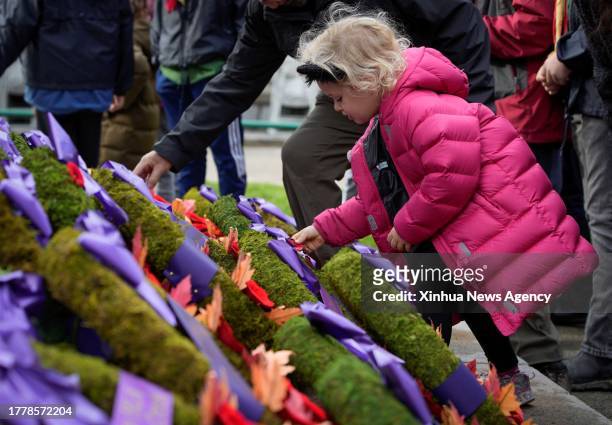 Girl places poppies in front of a cenotaph during the Remembrance Day ceremony at Victory Square in Vancouver, Canada, on Nov. 11, 2023.