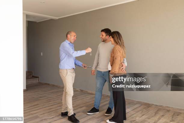 unkenntliche frau zeigt schlüssel zu ihrem neuen zuhause - übergeben stock-fotos und bilder