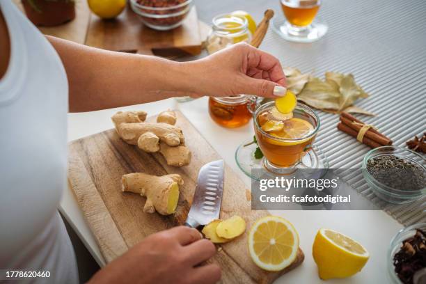 mujer preparando té caliente de jengibre y limón - ginger fotografías e imágenes de stock