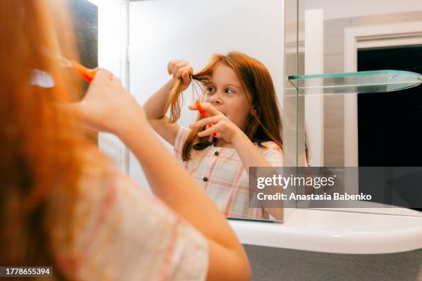 reflection of redhead girl cutting her hair - girl hair cut stock pictures, royalty-free photos & images