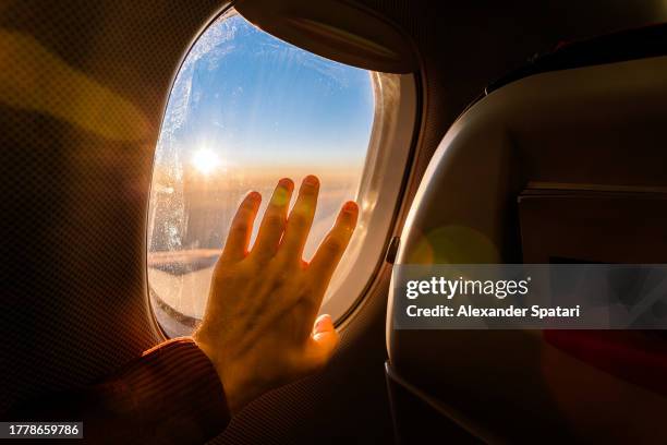 man reaching hand to airplane window during the flight, personal perspective view - clouds from aircraft point of view stock pictures, royalty-free photos & images