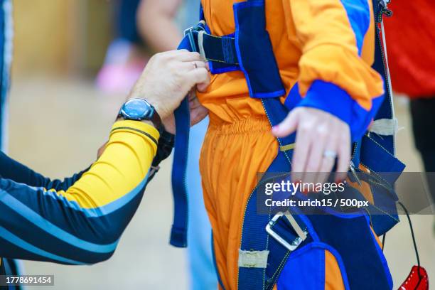 close-up of the instructor tightening the straps of the parachute suit for skydiver - skydive close up stock pictures, royalty-free photos & images