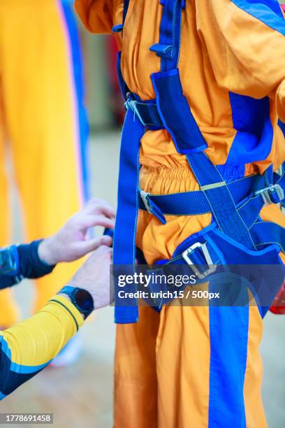 close-up of the instructor tightening the straps of the parachute suit for skydiver - skydive close up stock pictures, royalty-free photos & images