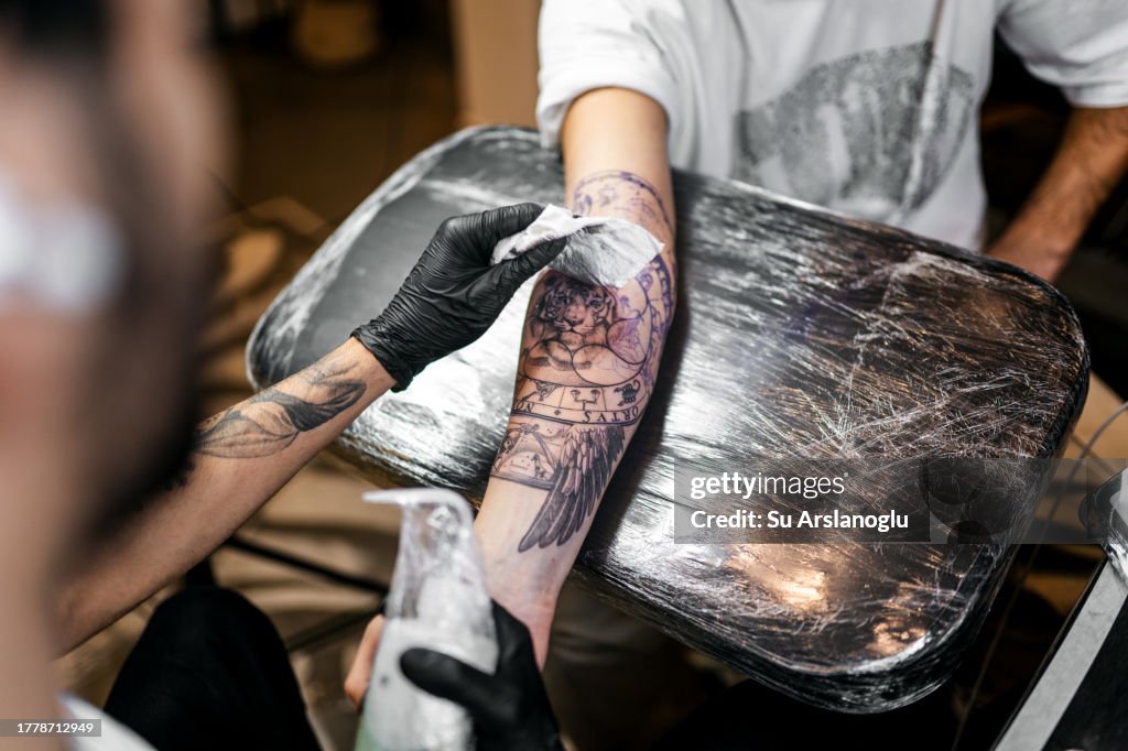 Young tattoo artist tattooing his customer in his studio