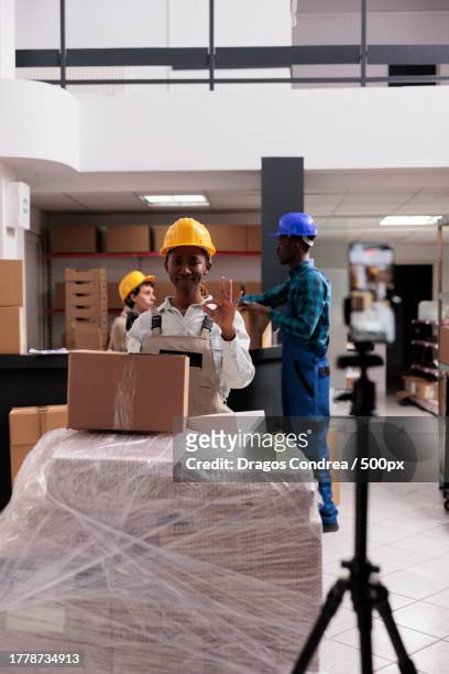close-up of smiling storehouse employee showing ok gesture and shooting stock checking video - ok werk stock-fotos und bilder