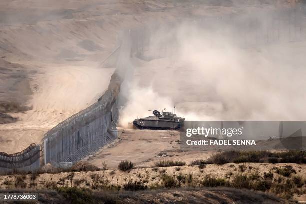 This picture taken on November 12, 2023 from a position along the border with the Gaza Strip in southern Israel shows an Israeli tank crossing the...