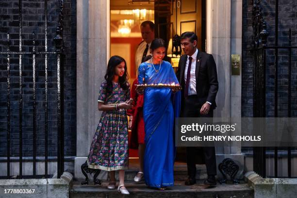 Britain's Prime Minister Rishi Sunak and his wife Akshata Murty carry a tray of candles outside 10 Downing Street, in central London, on November 12,...