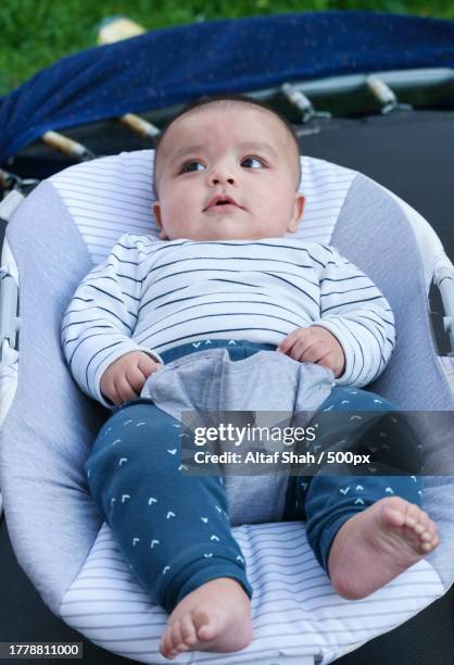 close-up of asian pakistani cute baby boy lying in chair in the home garden during cloudy day - cute pakistani boys fotografías e imágenes de stock