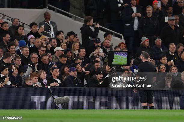 Referee Michael Oliver checks the VAR screen for a red card for Cristian Romero of Tottenham Hotspur which was later givenduring the Premier League...