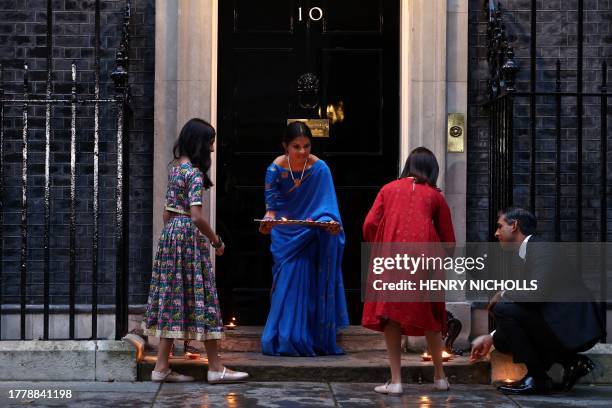 Britain's Prime Minister Rishi Sunak, his wife Akshata Murty and their daughters Anoushka Sunak and Krishna Sunak lay the candles outside 10 Downing...