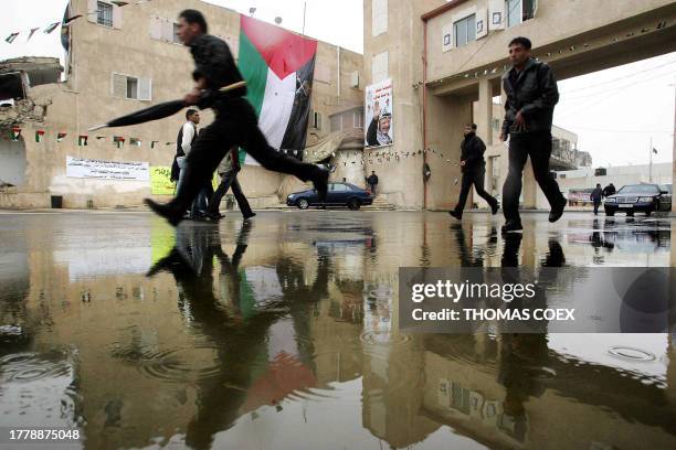 Palestinians run under the rain in front of the Muqataa compound, the Palestinian Authority's headquarters in the West Bank city of Ramallah, 17...