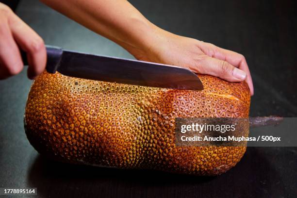 cropped hand peeling ripe chempedak fruit on table - jackfruit stock-fotos und bilder