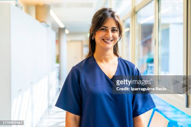 portrait of attractive dark-haired nurse smiling in hallway of hospital or medical center, medical team of medical clinic - executivo chefe de operações - fotografias e filmes do acervo