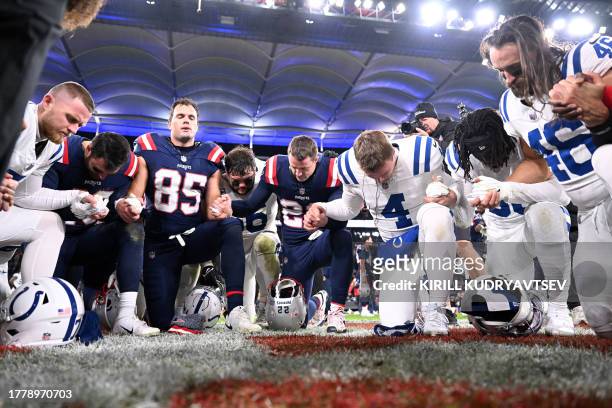 Players of both teams kneel and pray after the NFL American football match Indianapolis Colts vs New England Patriots at the Deutsche Bank Park in...