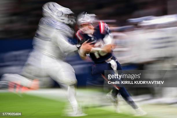 New England Patriots' quarterback Mac Jones is tackled by Indianapolis Colts' defensive tackle Adetomiwa Adebawore during the NFL American football...