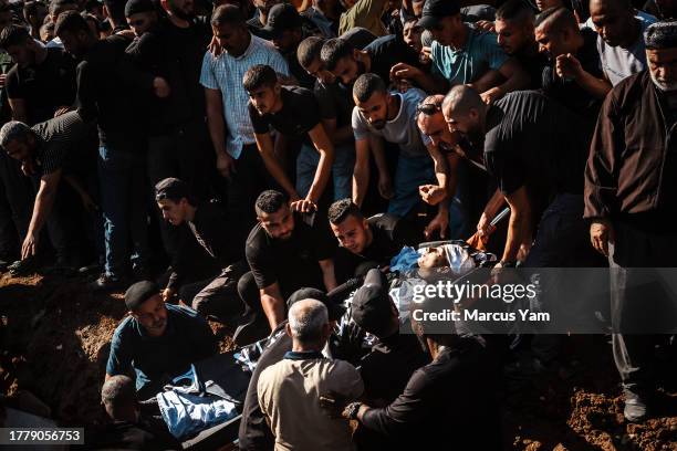 Omar Abu Aqel center, helps bury his brother Rafat Abu Aqel, in the midst of a cacophony of thunderous gunfire & sorrowful praise to the Almighty...