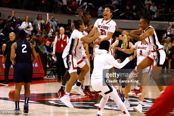 Saniya Rivers and Madison Hayes of the NC State Wolfpack celebrate with teammates following their 92-81 victory against the UConn Huskies at Reynolds...