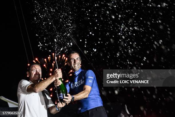 French skipper of the Banque Populaire Ultim multihull Armel Le Cleac'h sprays Champagne with his co-skipper Sebastien Josse as they celebrate after...