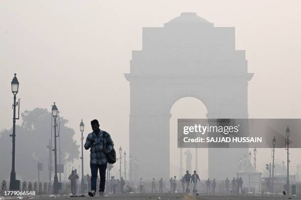 People walk along the Kartavya Path in front of the India Gate amid heavy smoggy conditions in New Delhi on November 13, 2023. Delhi regularly ranks...