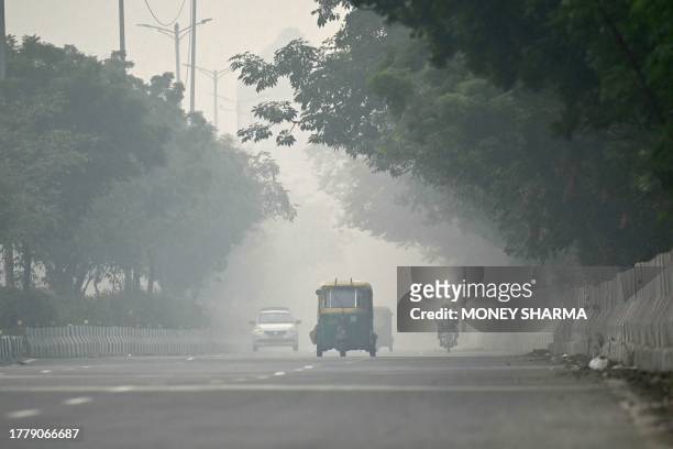 Commuters make their way along a road amid heavy smoggy conditions in New Delhi on November 13, 2023. Delhi regularly ranks among the most polluted...