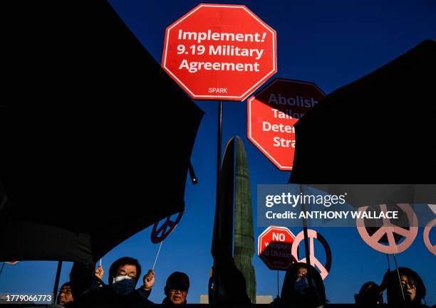 Activists protest in front of police holding up umbrellas , near the presidential office in Seoul on November 13 as US Defense Secretary Lloyd...