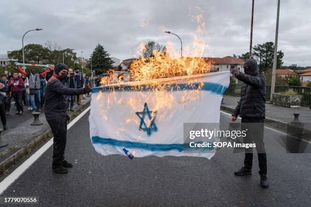 Two hooded demonstrators burned a flag of Israel at the bridge linking Spain and France. Pro-Palestine demonstrators gathered at Construcciones y...