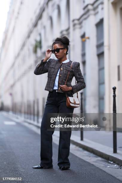 Ellie Delphine wears sunglasses, a white t-shirt, a tweed jacket with bronze buttons from Veronica Beard, flared denim / jeans pants from Zara, a...