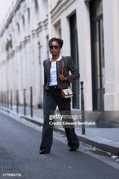 Ellie Delphine wears sunglasses, a white t-shirt, a tweed jacket with bronze buttons from Veronica Beard, flared denim / jeans pants from Zara, a...