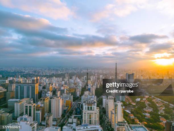 coucher de soleil dans la ville avec des bâtiments et à côté d’un quartier avec des maisons et un parc verdoyant - são paulo photos et images de collection