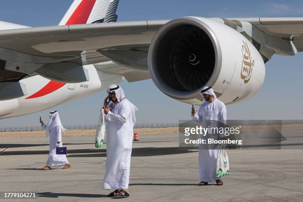 Attendees on smartphones alongside an Airbus A380-800 passenger aircraft, operated by Emirates Airlines, at the Dubai Air Show in Dubai, United Arab...
