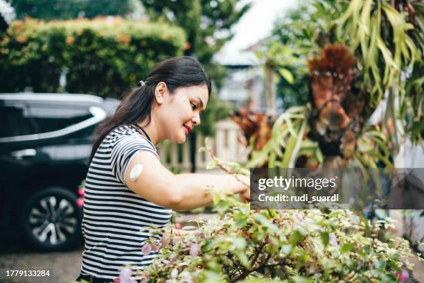 day in the life of woman with cgm examining flowers in green house - continuous glucose monitor stock pictures, royalty-free photos & images